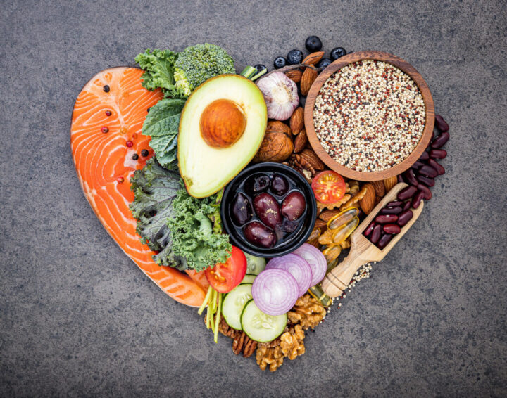 Heart shape of ketogenic low carbs diet concept. Ingredients for healthy foods selection on dark stone background. Balanced healthy ingredients of unsaturated fats for the heart and blood vessels.